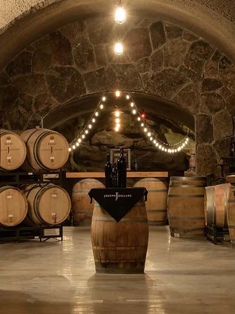 Joseph Cellars wine cave with barrels and stone arches