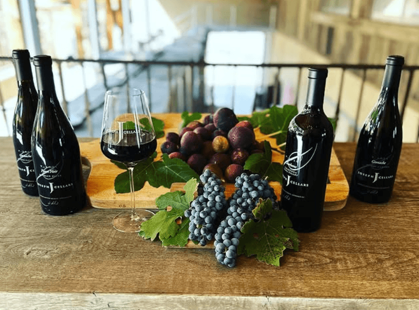 Wine bottles and glass with grapes at the Joseph Cellars tasting bar